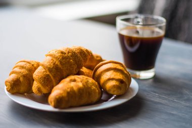 Makro vurdu. Amerikan kahve ve siyah bir zemin üzerine taze kruvasanlar. Moody renk dostum. Tatlı ve kahve. Kahvaltı kavramı.