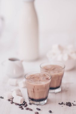 Dikey vurdu. Açık renkli. Buzlu kahve. Marshmelow ve kahve fasulye masanın üzerinde. Soğutma içki kavramı. Yaz içeceği. Soğuk kahve süt ve çikolata ile.