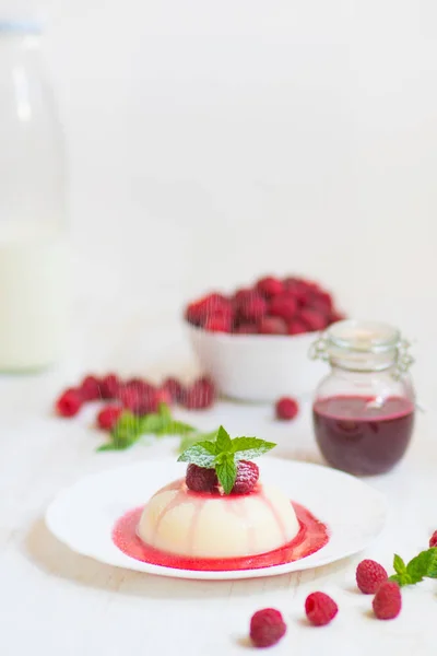 Close up. Flying powdered sugar. Panakota with raspberries and mint. Vertical shot. Summer dessert. Light background. — Stock Photo, Image