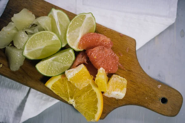 Pila de rodajas de cítricos. Naranjas y limones limas, pomelo, pomelo. Sobre mesa de madera — Foto de Stock
