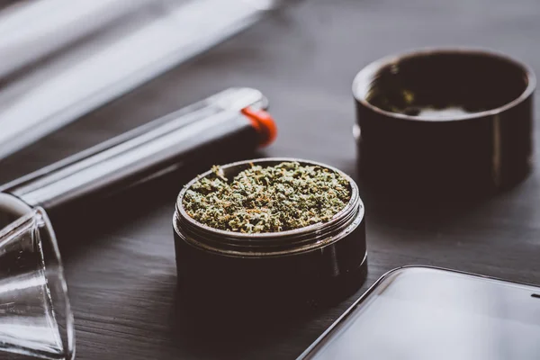 Buds Cannabis em moedor sobre a mesa Marijuana com um moedor. Fundo escuro. Fecha. Tonificação cor de esteiras . — Fotografia de Stock