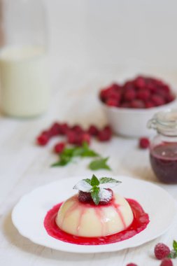 Ahududu ve nane ile panakota. Dikey vurdu. Yaz tatlı. Açık renkli. Yakın çekim. Uçan pudra şekeri.