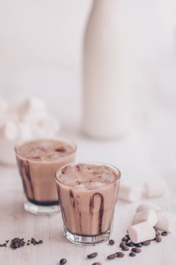 Soğuk kahve süt ve çikolata. Dikey vurdu. Açık renkli. Buzlu kahve. Soğutma içki kavramı. Marshmelow ve kahve fasulye masanın üzerinde. Yaz içeceği.