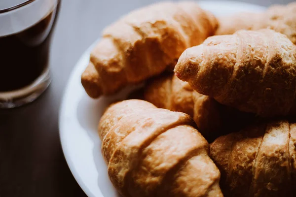 Macro shot. American coffee and fresh croissants on a black background. The concept of breakfast. Dessert and coffee. Mate moody color. — Stock Photo, Image