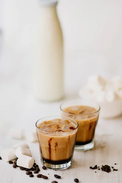 Fondo claro. Café helado. Marshmelow y granos de café en la mesa. Concepto de bebida refrescante. Bebida de verano. Café frío con leche y chocolate. Disparo vertical . — Foto de Stock