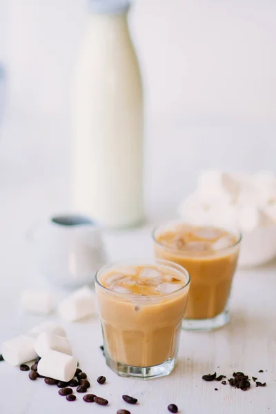 Cold coffee with milk and chocolate. Light background. Iced coffee. Concept of a cooling drink. Marshmelow and coffee beans on the table. Summer drink.