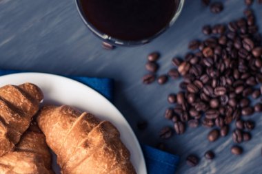Tatlı ve kahve çekirdekleri. Moody renk dostum. Kahvaltı kavramı. Taze kruvasan ve kahve siyah bir arka plan üzerinde makro çekim.