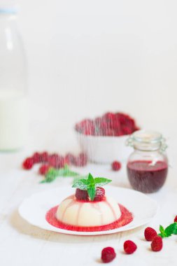 Uçan pudra şekeri. Ahududu ve nane ile panakota. Dikey vurdu. Yaz tatlı. Açık renkli. Yakın çekim.