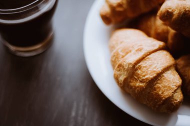 Tatlı ve kahve. Makro vurdu. Amerikan kahve ve siyah bir zemin üzerine taze kruvasanlar. Kahvaltı kavramı. Dostum moody renk.