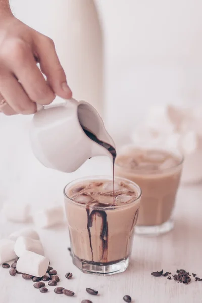Iced coffee. Concept of a cooling drink. Marshmelow and coffee beans on the table. Summer drink. Cold coffee with milk and chocolate. Light background.