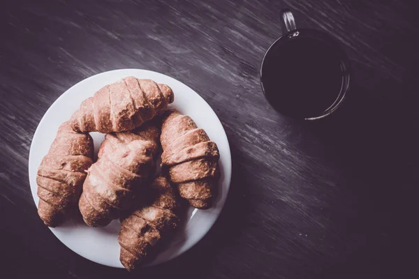 Das Konzept des Frühstücks. Makroschuss. Mate launische Farbe. Kaffee und frische Croissants auf schwarzem Hintergrund. Dessert und Kaffee. — Stockfoto