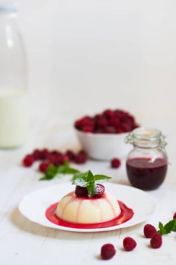 Yakın çekim. Uçan pudra şekeri. Ahududu ve nane ile panakota. Dikey vurdu. Yaz tatlı. Açık renkli.