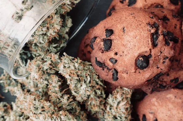 Bolachas de chocolate com marijuana. Doces com cannabis. Botões de canábis num fundo preto. Cozimento com a adição de CBD. Doces com erva. macro — Fotografia de Stock