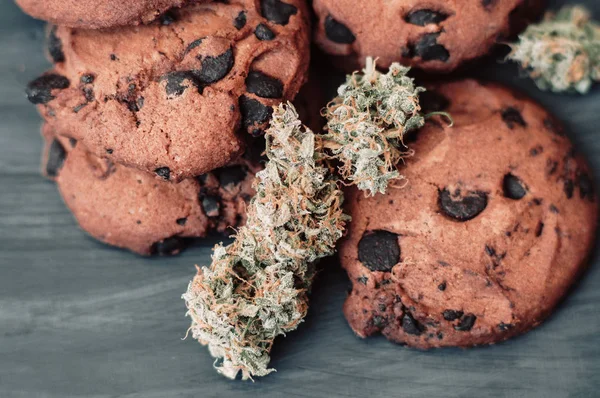 Cannabis-Knospen auf schwarzem Hintergrund. Backen mit Zugabe von cbd. Süßigkeiten mit Unkraut. Schokoladenkekse mit Marihuana. Süßigkeiten mit Cannabis. — Stockfoto