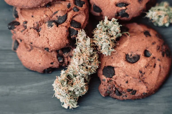 Botões de canábis num fundo preto. Cozimento com a adição de CBD. Doces com erva. Bolachas de chocolate com marijuana. Doces com cannabis . — Fotografia de Stock