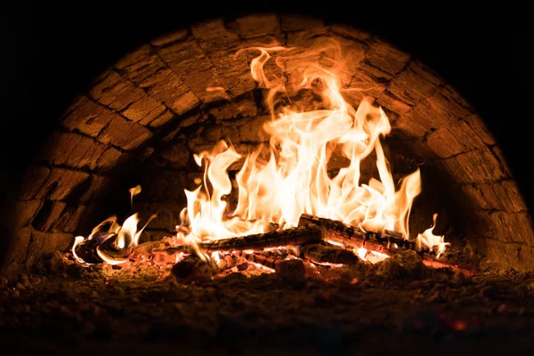 Close up. Fire in the oven. Pizza in the coals. Dark background. Concepts of cooking on a fire in the oven. — Stock Photo, Image