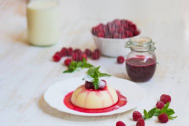Yaz tatlı. Açık renkli. Yakın çekim. Uçan pudra şekeri. Ahududu ve nane ile panakota. Dikey vurdu.