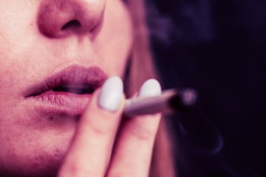 Bir kadın sigara ot esrar esrar ve onun elinde bir çakmak. Siyah bir arka plan üzerinde duman. Tıbbi esrar kullanım ve yasallaştırma esrar kavramları. Pembe siyah bir arka plan renklendirme