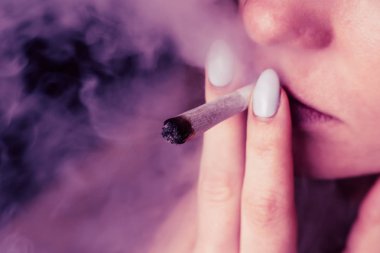 Tıbbi esrar kullanım ve yasallaştırma esrar kavramları. Siyah bir arka plan üzerinde duman. Bir kadın sigara esrar esrar, esrar ve onun elinde bir çakmak. Pembe siyah bir arka plan renklendirme