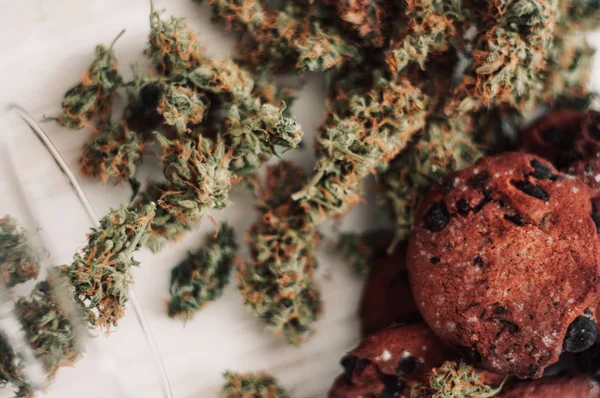 Bakning med tillägg av Cbd. godis med ogräs. Choklad cookies med marijuana. Godis med cannabis. Cannabis knoppar på en svart bakgrund. — Stockfoto