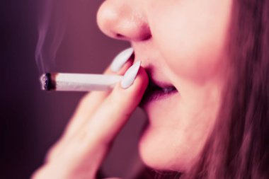 Esrar, elinde esrar Bir kadın sigara içiyor. Siyah arka planda sigara içmek. Tıbbi marihuana kullanımı ve esrar kullanımının yasallaştırılması kavramları. Siyah arka planda Pembe renklendirme