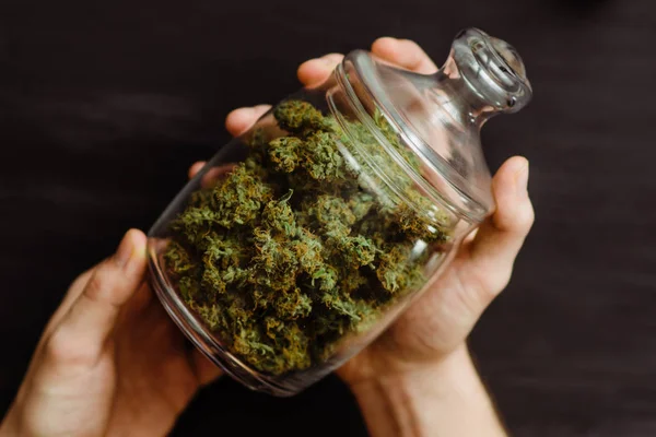 Begreppen legalisera ogräs. En bank med färska knoppar Cannabis i händerna på en man. En massa marijuana. Ovanifrån. Närbild. Svart bakgrund . — Stockfoto