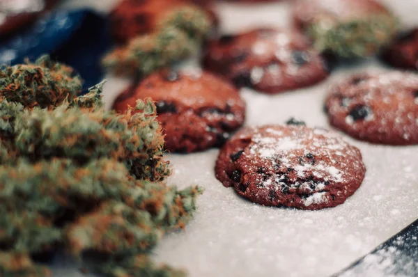 Süßigkeiten mit Cannabis. Cannabis-Knospen auf schwarzem Hintergrund. Backen mit Zugabe von cbd. Süßigkeiten mit Unkraut. Schokoladenkekse mit Marihuana. — Stockfoto