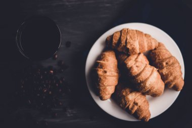 Makro vurdu. Moody renk dostum. taze kruvasan ve kahve siyah bir arka plan. Kahvaltı kavramı. Tatlı ve kahve.