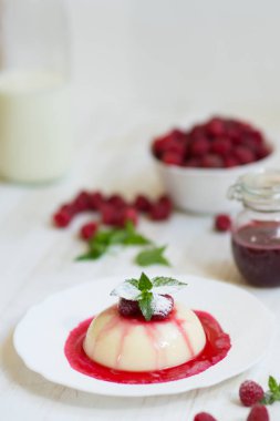 Uçan pudra şekeri. Ahududu ve nane ile panakota. Dikey vurdu. Yaz tatlı. Açık renkli. Yakın çekim.