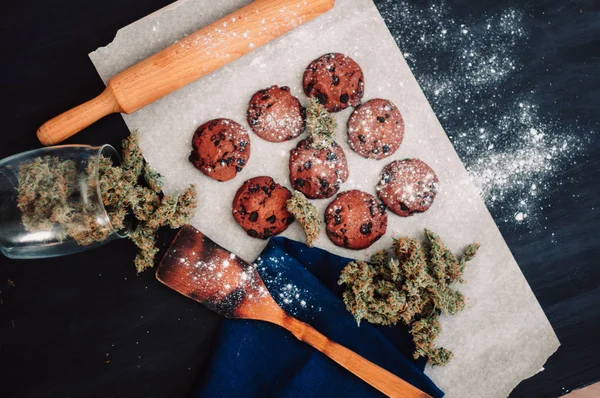 Bolachas de chocolate com marijuana. Doces com cannabis. Botões de canábis num fundo preto. Cozimento com a adição de CBD. Doces com erva. vista superior — Fotografia de Stock