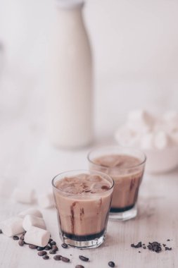 Dikey vurdu. Açık renkli. Buzlu kahve. Marshmelow ve kahve fasulye masanın üzerinde. Soğutma içki kavramı. Yaz içeceği. Soğuk kahve süt ve çikolata ile.