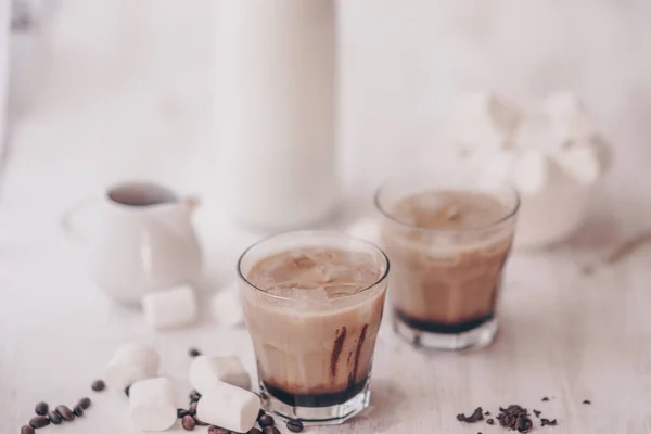 Café frío con leche y chocolate. Fondo claro. Café helado. Marshmelow y granos de café en la mesa. Concepto de bebida refrescante. Bebida de verano . — Foto de Stock