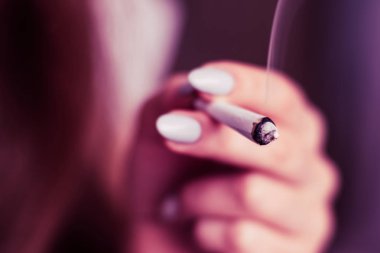 elinde ortak. Bir kadın esrar ot çekiyor bir. Siyah bir arka plan üzerinde duman. Tıbbi esrar kullanım ve yasallaştırma esrar kavramları. Pembe siyah bir arka plan renklendirme