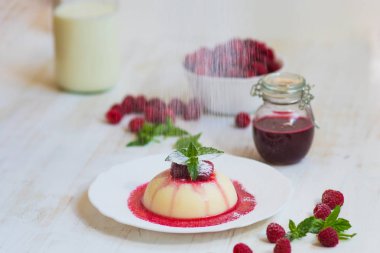 Ahududu ve nane ile panakota. Dikey vurdu. Yaz tatlı. Açık renkli. Yakın çekim. Uçan pudra şekeri.