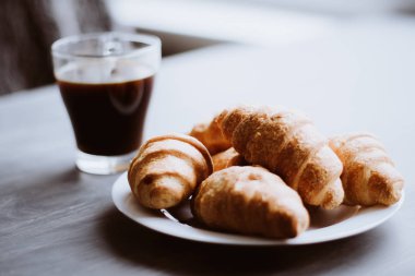 Tatlı ve kahve. Kahvaltı kavramı. Makro vurdu. Amerikan kahve ve siyah bir zemin üzerine taze kruvasanlar. Dostum moody renk.
