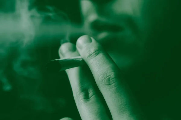 一个男人在手上抽大麻 黑色背景下的烟雾 医疗用大麻的概念和大麻的合法化 在黑色背景上 — 图库照片