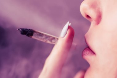 Tıbbi esrar kullanım ve yasallaştırma esrar kavramları. Siyah bir arka plan üzerinde duman. Bir kadın sigara esrar esrar, esrar ve onun elinde bir çakmak. Pembe siyah bir arka plan renklendirme