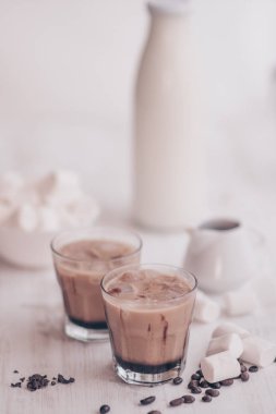 Buzlu kahve. Marshmelow ve kahve fasulye masanın üzerinde. Soğutma içki kavramı. Yaz içeceği. Soğuk kahve süt ve çikolata. Dikey vurdu. Açık renkli.