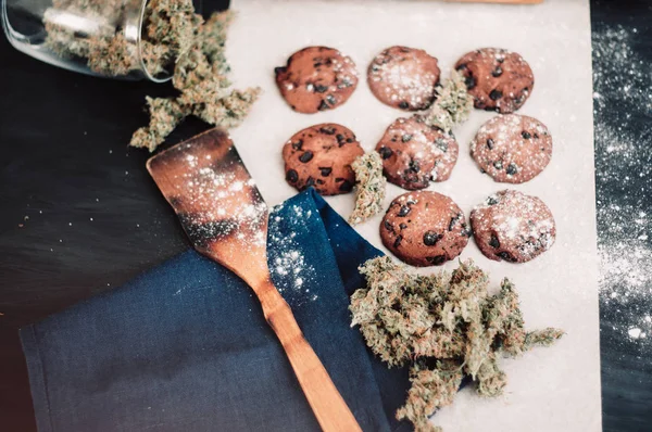 Brotes de cannabis sobre un fondo negro. Hornear con la adición de CBD. Dulces con hierba. Galletas de chocolate con marihuana. Dulces con cannabis. vista superior —  Fotos de Stock