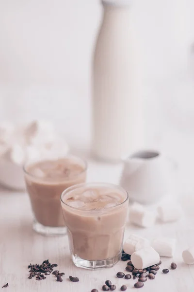 Fondo claro. Café helado. Concepto de bebida refrescante. Marshmelow y granos de café en la mesa. Bebida de verano. Café frío con leche y chocolate . — Foto de Stock