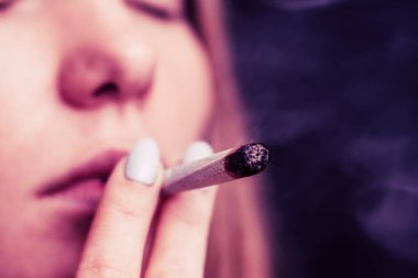 Tıbbi esrar kullanım ve yasallaştırma esrar kavramları. Siyah bir arka plan üzerinde duman. Bir kadın sigara esrar esrar, esrar ve onun elinde bir çakmak. Pembe siyah bir arka plan renklendirme