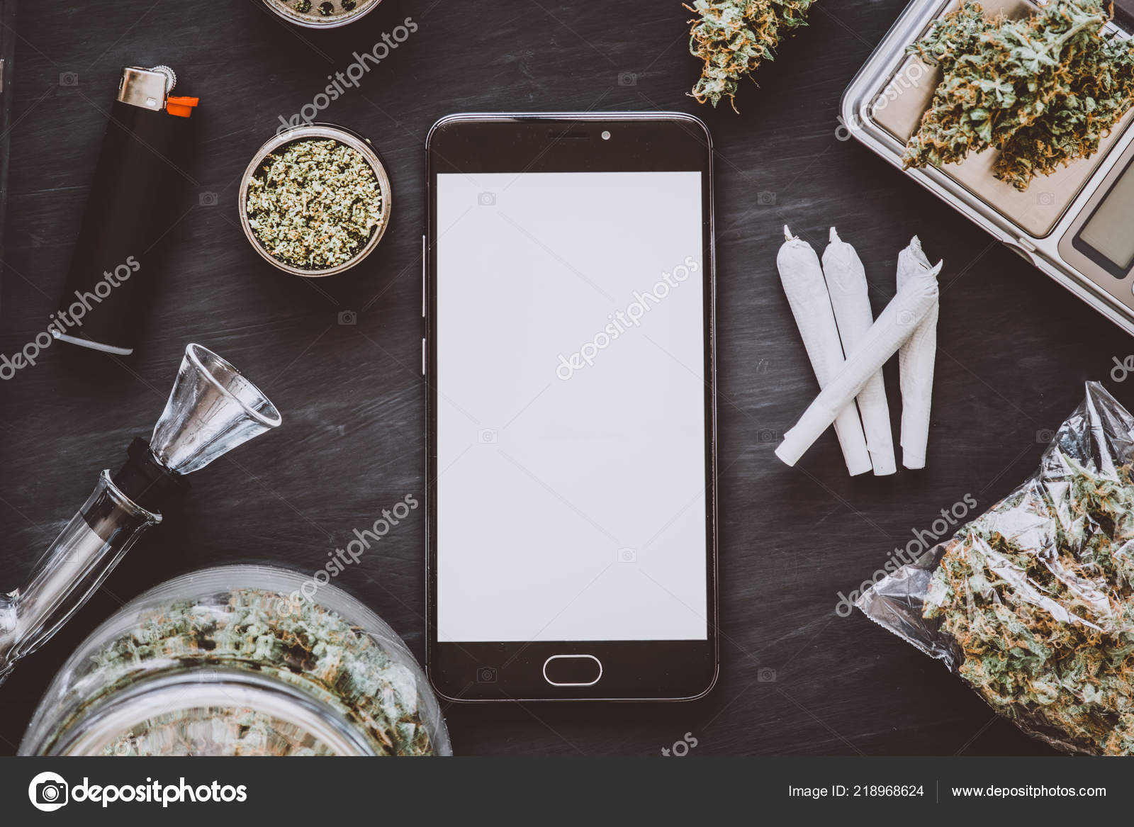 Smartphone With White Screen For Mockup Cannabis Buds On The Scales Lie On The Table With A Grinder Joint And Smartphone Marijuana In The Package Top View Dark Background Close Up Royalty