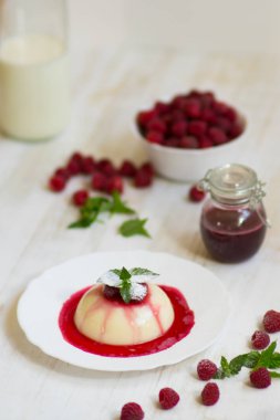 Yakın çekim. Uçan pudra şekeri. Ahududu ve nane ile panakota. Dikey vurdu. Yaz tatlı. Açık renkli.