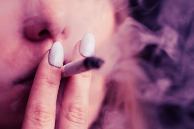 Esrar, elinde esrar Bir kadın sigara içiyor. Siyah arka planda sigara içmek. Tıbbi marihuana kullanımı ve esrar kullanımının yasallaştırılması kavramları. Siyah arka planda Pembe renklendirme