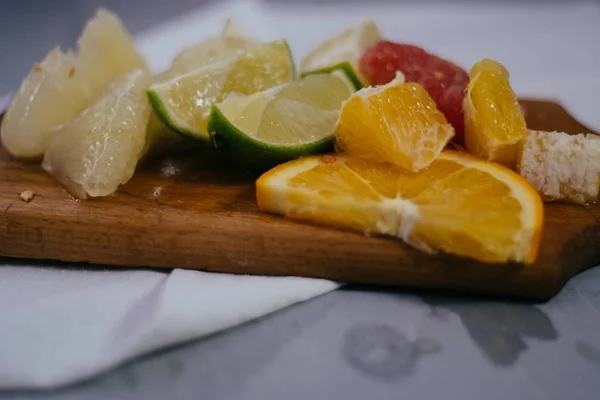 Pila de rodajas de cítricos. Naranjas y limones limas, pomelo, pomelo. Sobre mesa de madera — Foto de Stock