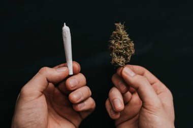 Esrar kullanım kavramı. Siyah bir arka plan üzerinde. üstten görünüm esrar bud ve ortak bir adam elinde.