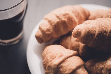 Tatlı ve kahve. Moody renk dostum. Makro vurdu. Amerikan kahve ve siyah bir zemin üzerine taze kruvasanlar. Kahvaltı kavramı.