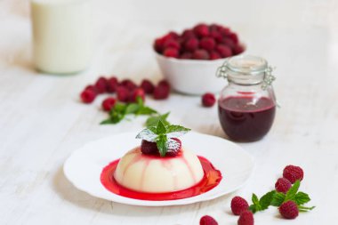 Yakın çekim. Uçan pudra şekeri. Ahududu ve nane ile panakota. Dikey vurdu. Yaz tatlı. Açık renkli.