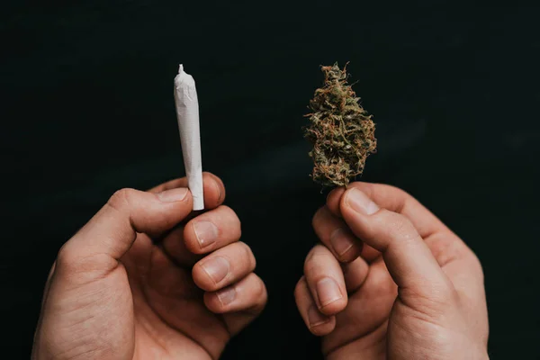 O conceito de uso de maconha. Num fundo preto. vista superior Cannabis bud e articulação nas mãos de um homem . — Fotografia de Stock