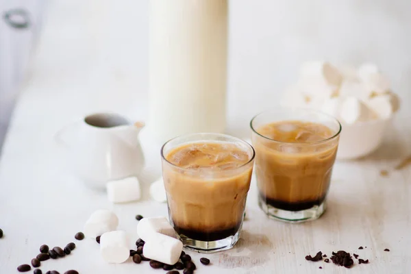 Cold coffee with milk and chocolate. Light background. Iced coffee. Marshmelow and coffee beans on the table. Concept of a cooling drink. Summer drink.